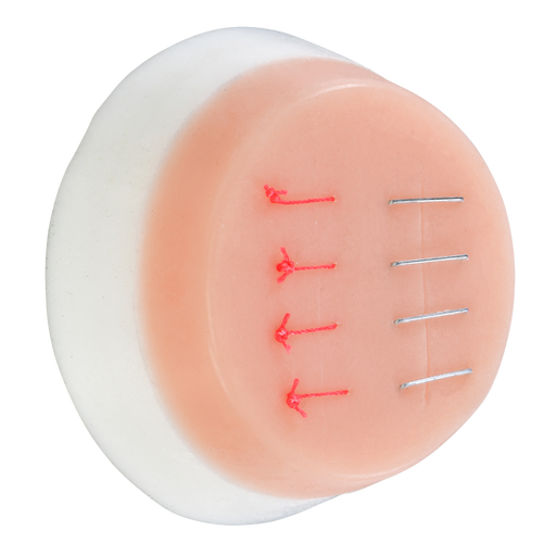 A pale pink, circular training pad displays three suture lines and three rows of simulated staples; it sits on a white base.