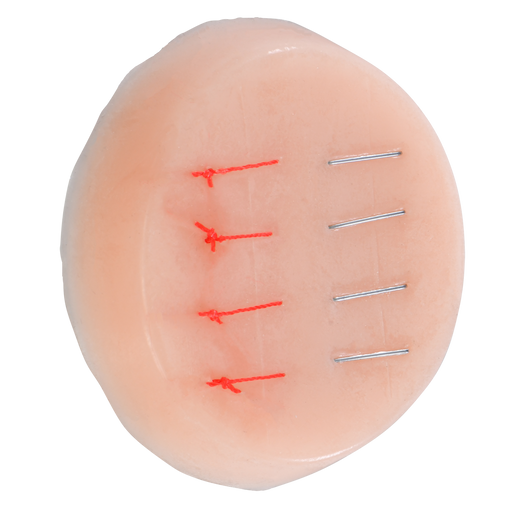 A training pad displays simulated sutures and staples. Three red sutures and three metallic staples are affixed to the pale pink, circular pad.