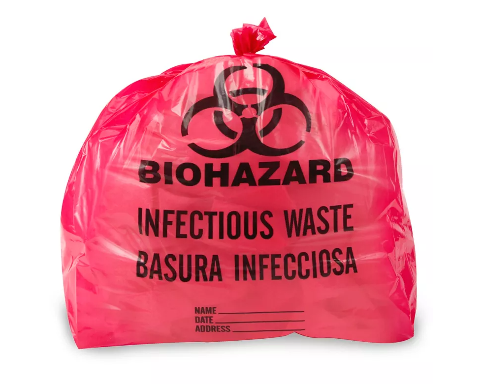 A pink biohazard bag contains infectious waste. The bag displays "BIOHAZARD," "INFECTIOUS WASTE," "BASURA INFECCIOSA," and spaces for name, date, and address.