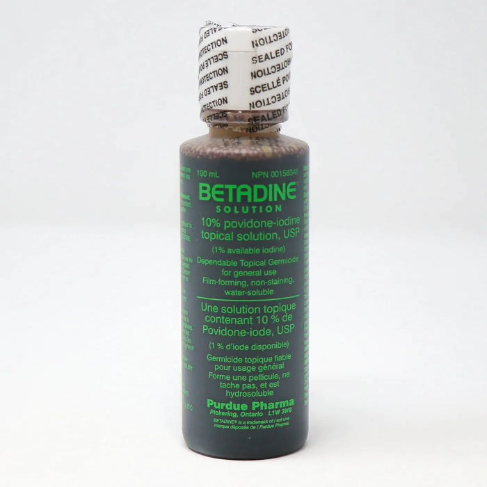 A dark-brown bottle of Betadine solution sits on a white surface. The label indicates it's a 10% povidone-iodine topical solution, a germicide for general use. The bottle is sealed.