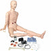 A medical training mannequin, positioned sitting, is surrounded by medical tools including a sphygmomanometer, tubing, and wound simulators.