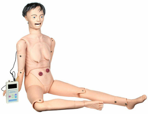 A female medical training mannequin sits with legs extended, connected to a small electronic device. The mannequin displays realistic anatomical details.